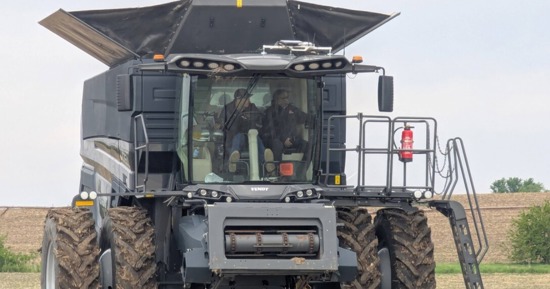 Santosh Pitla (right), professor of biological systems engineering, rides in a tractor at the grand opening of PTx Trimble's facility in Seward last spring. (Courtesy)